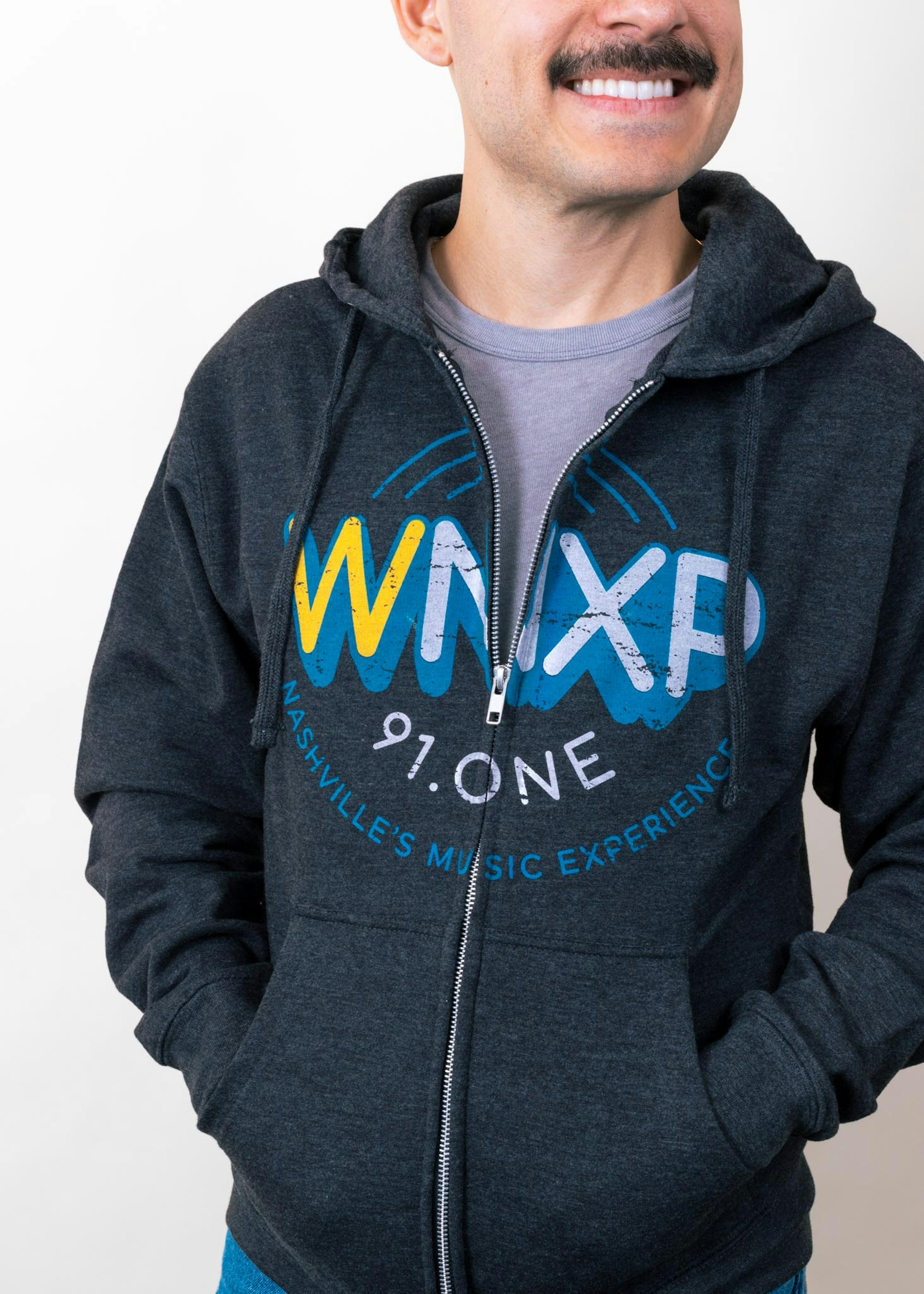A man wears a radio station zip up hoodie with over the zipper printing