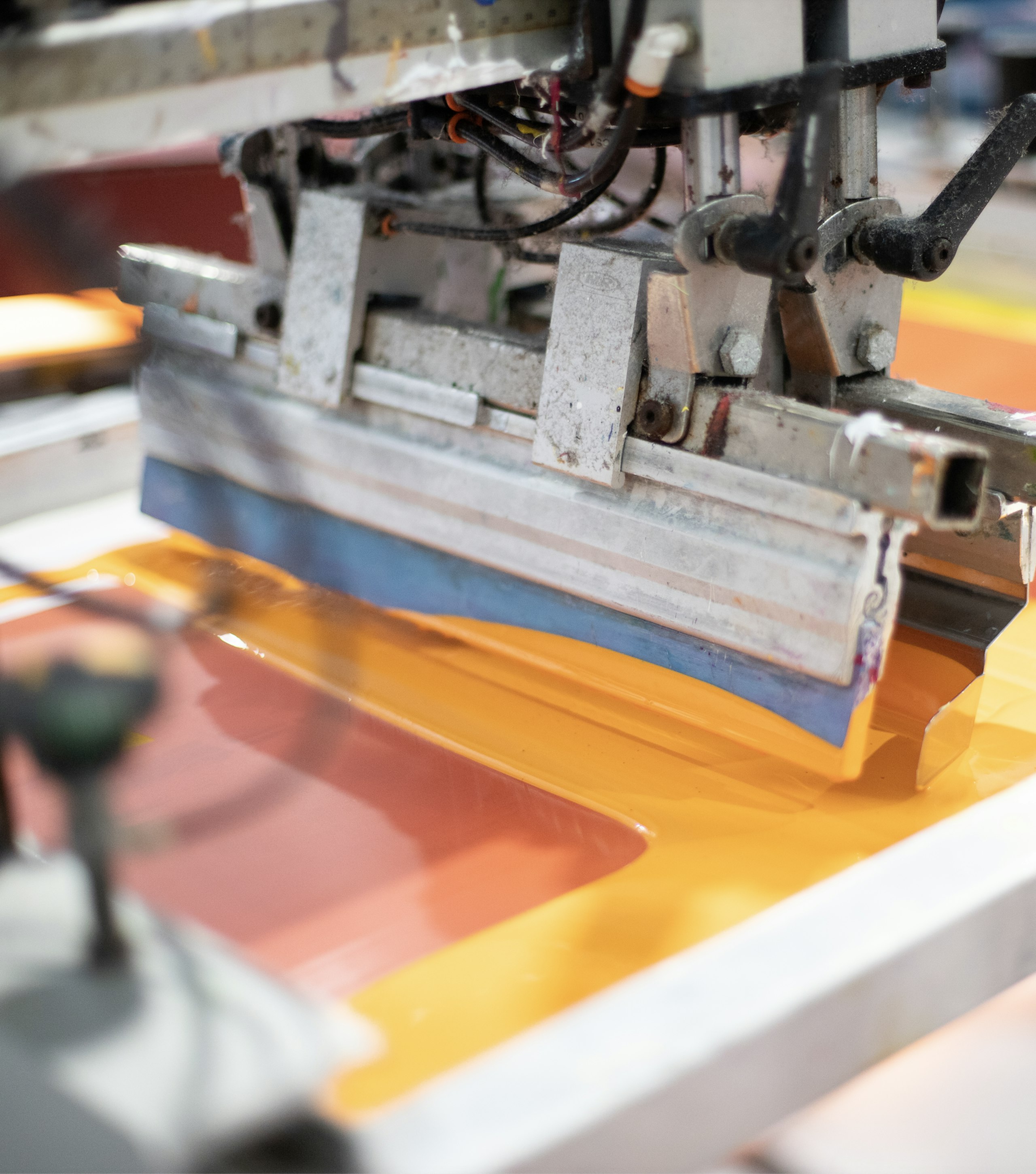 Yellow-orange ink floods a screen ready to be printed