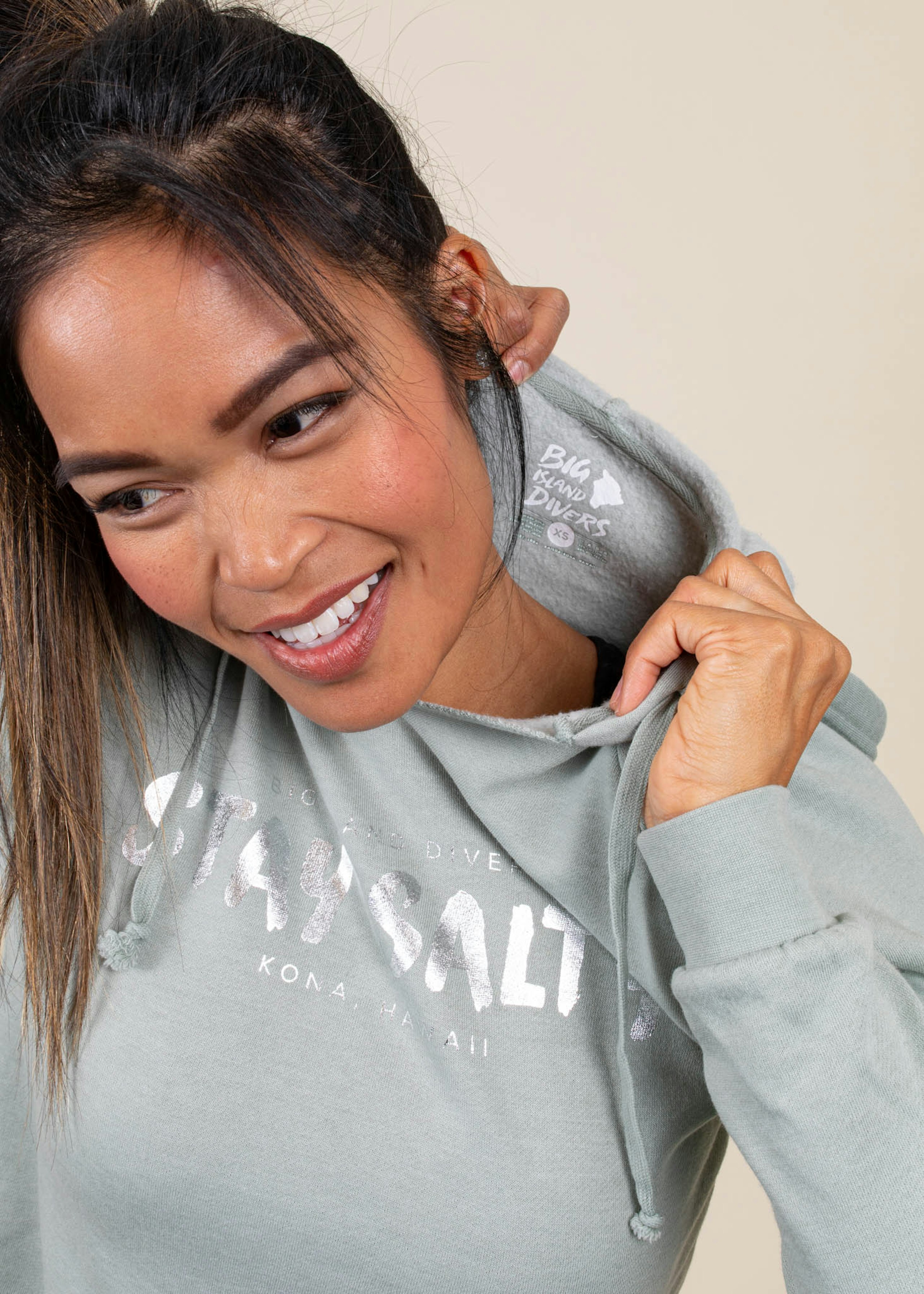A girl wears a metallic printed sweatshirt and shows off the custom tag