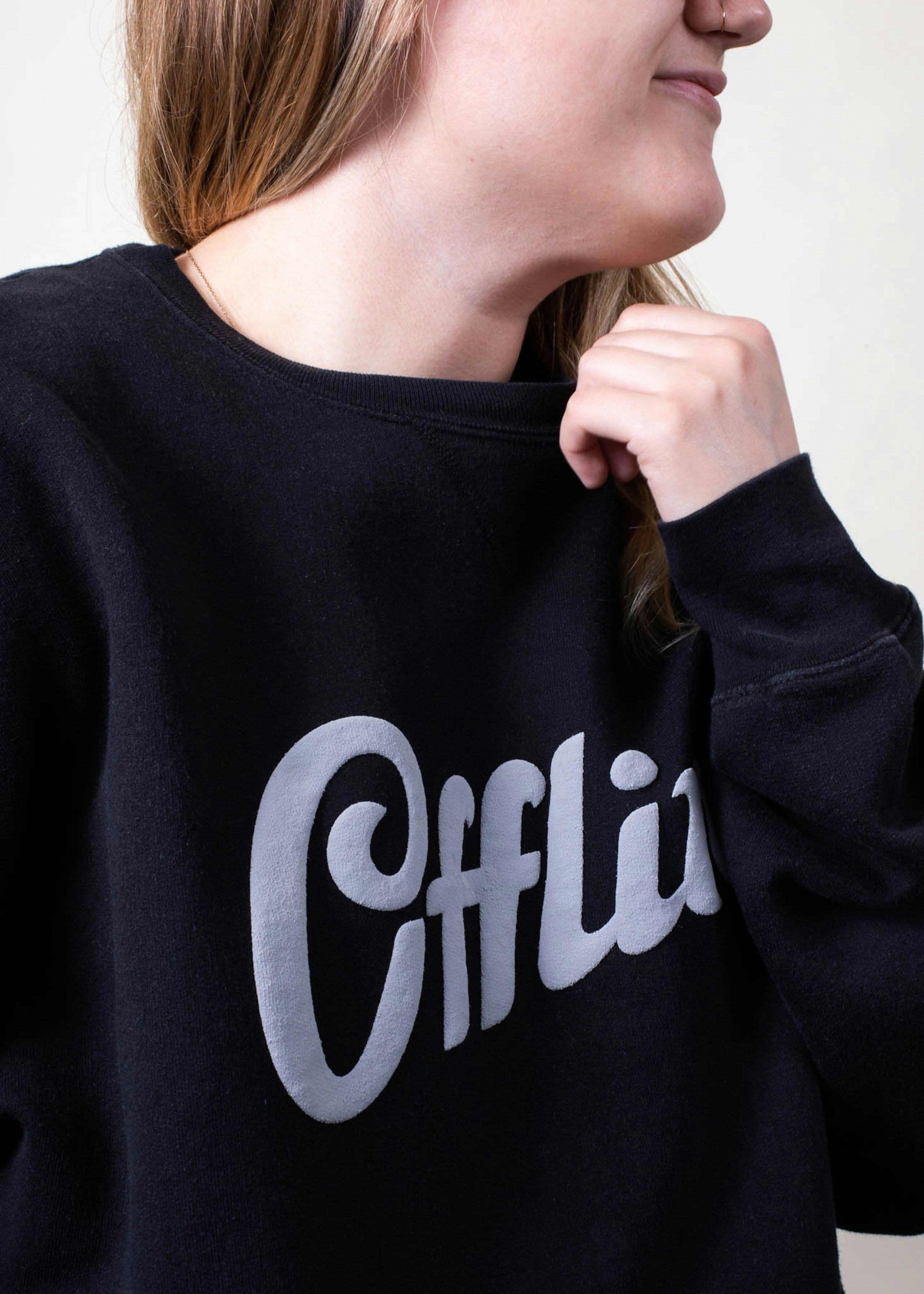 A girl wears a black sweatshirt with a white puff ink design printed on it