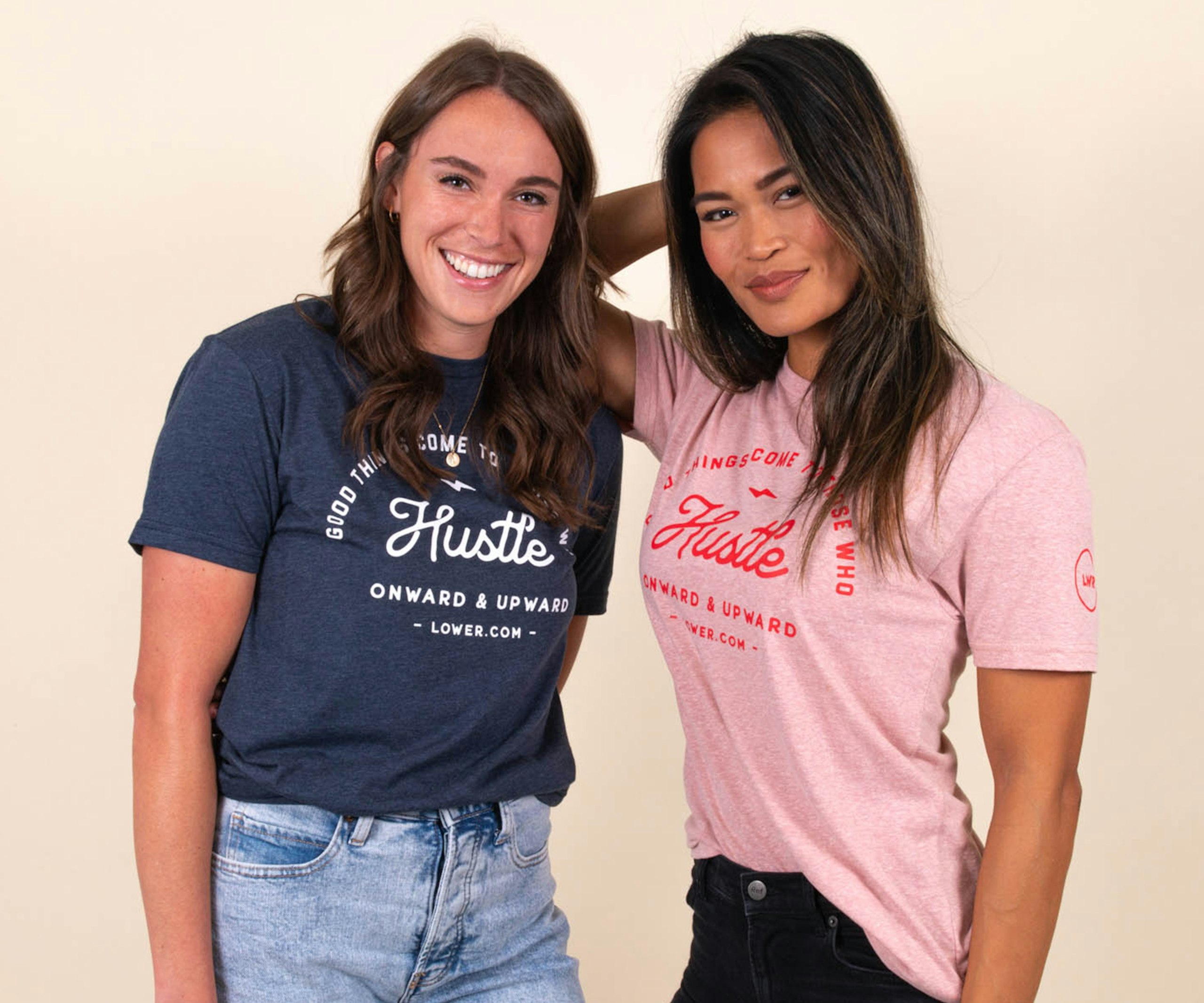Two girls wear matching shirts that say "hustle," one blue shirt, one pink