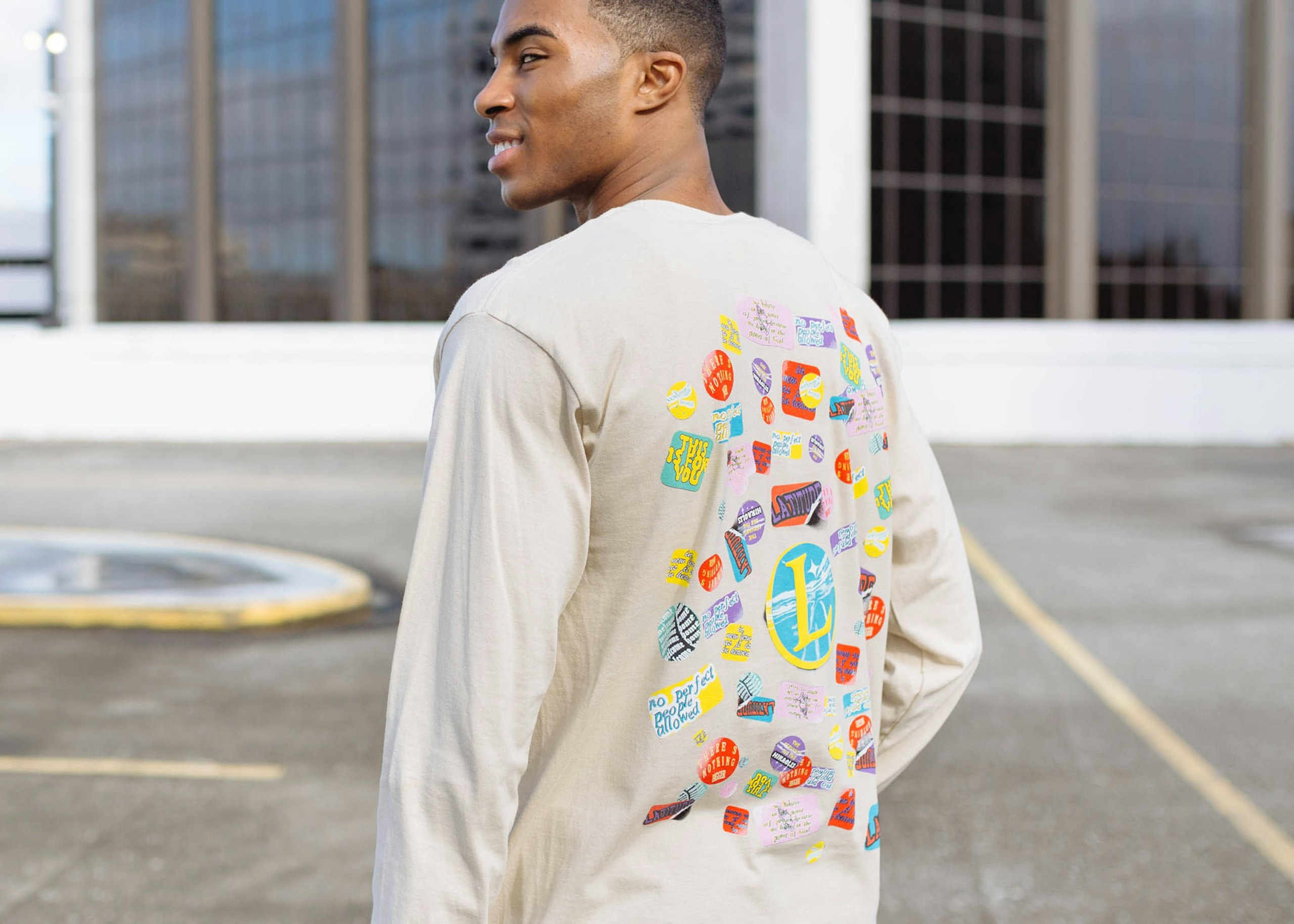 A man wears a shirt with a very colorful puff printed design on the back 