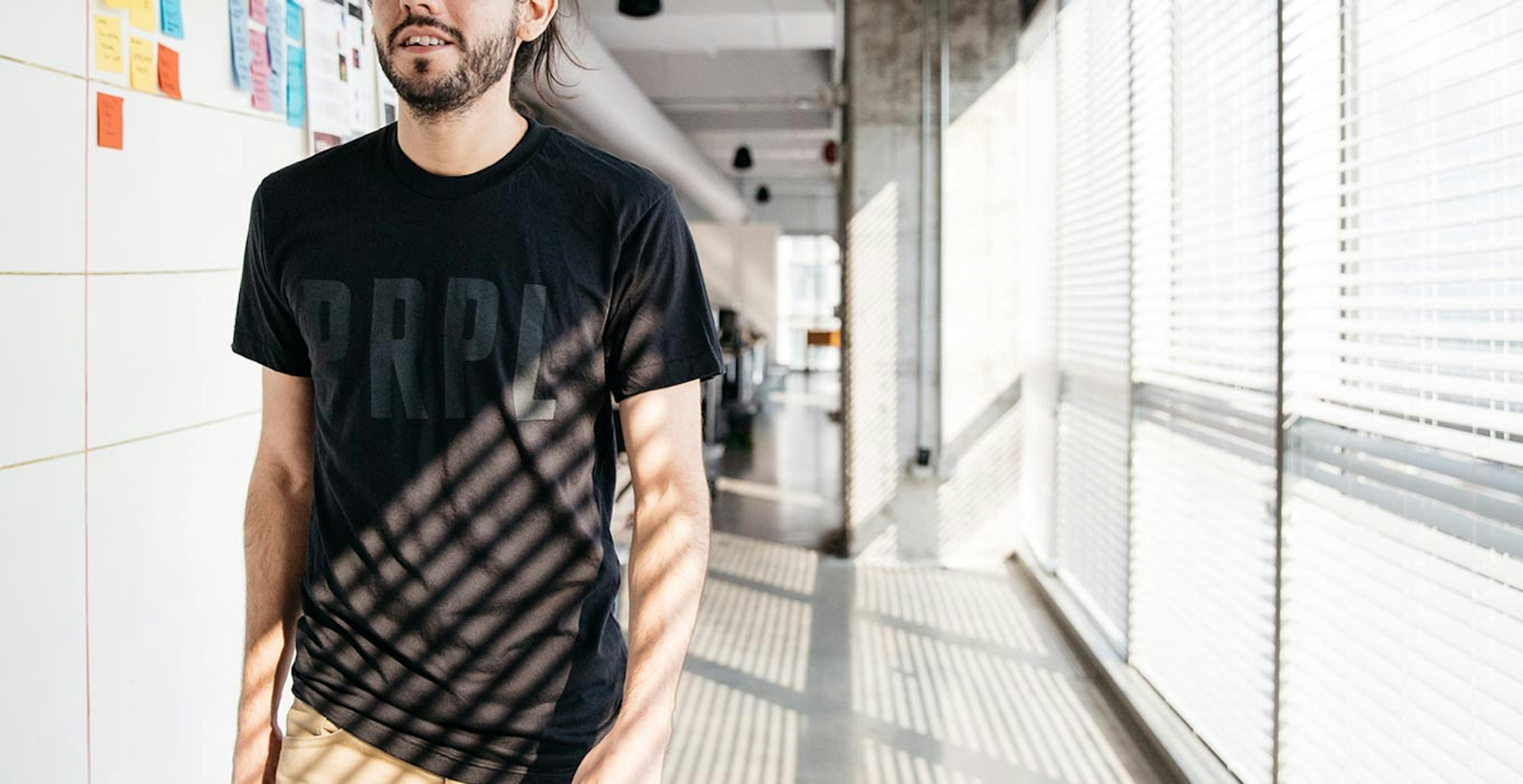A man walks down the hallway wearing a shirt that says "PRPL"