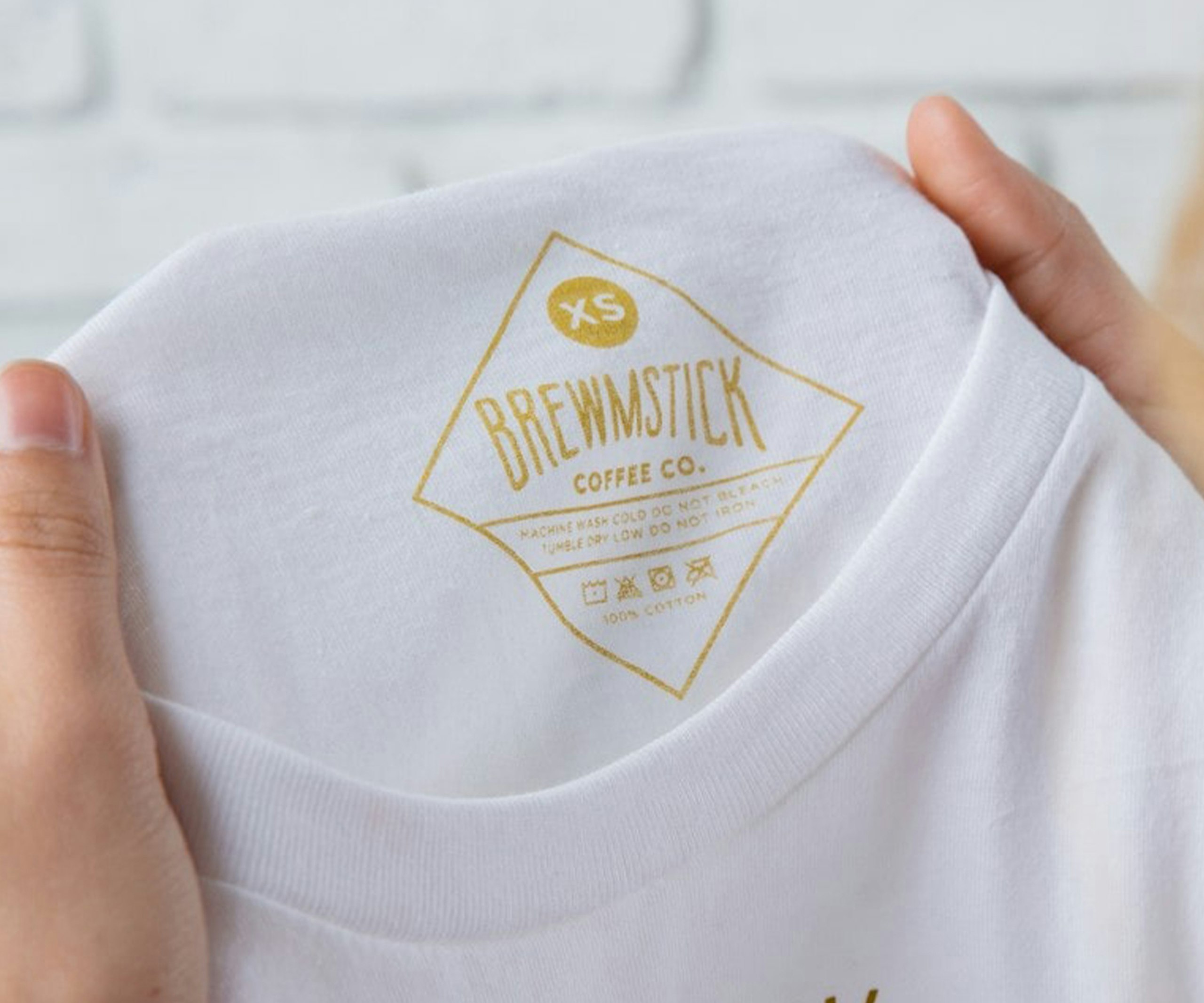 A custom printed tag in gold on a white t-shirt