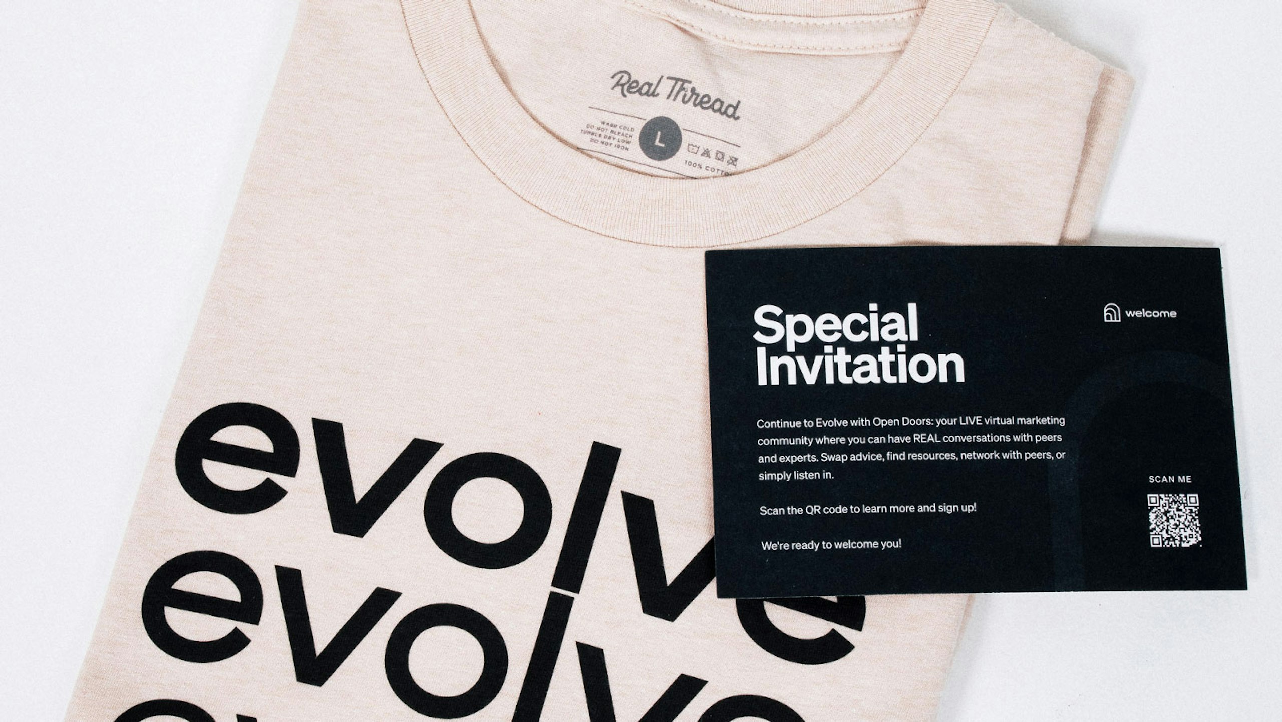 white folded shirt with evolve printed in black. laying on top is a black card