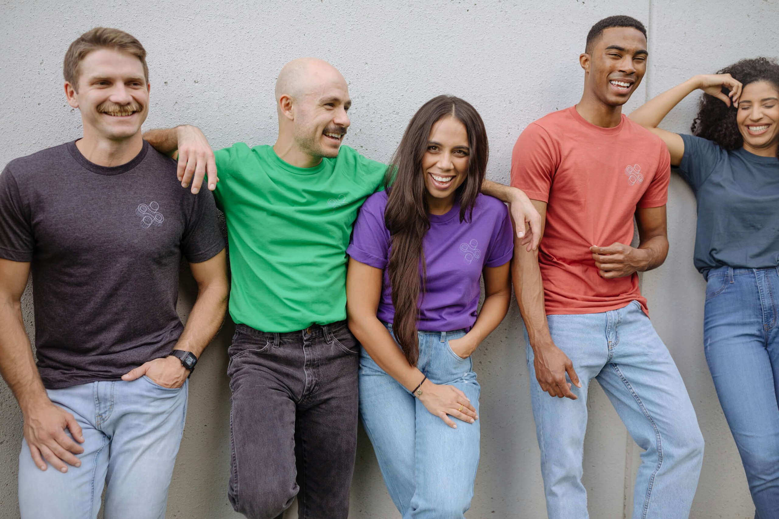 A group of people all wear a shirt printed with the same design, but on different colored garments