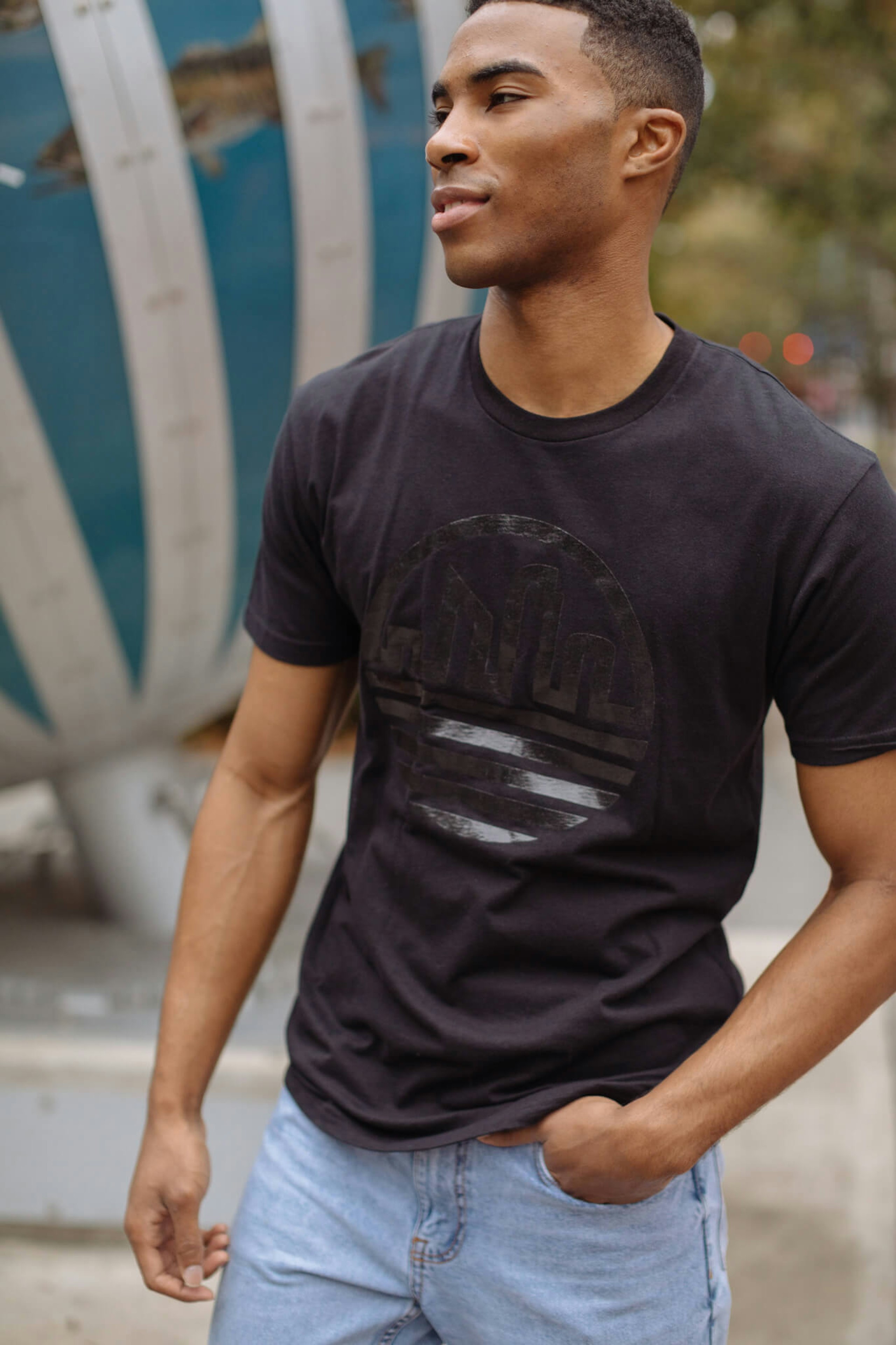 A man wears a black t-shirt with a black metallic printed design