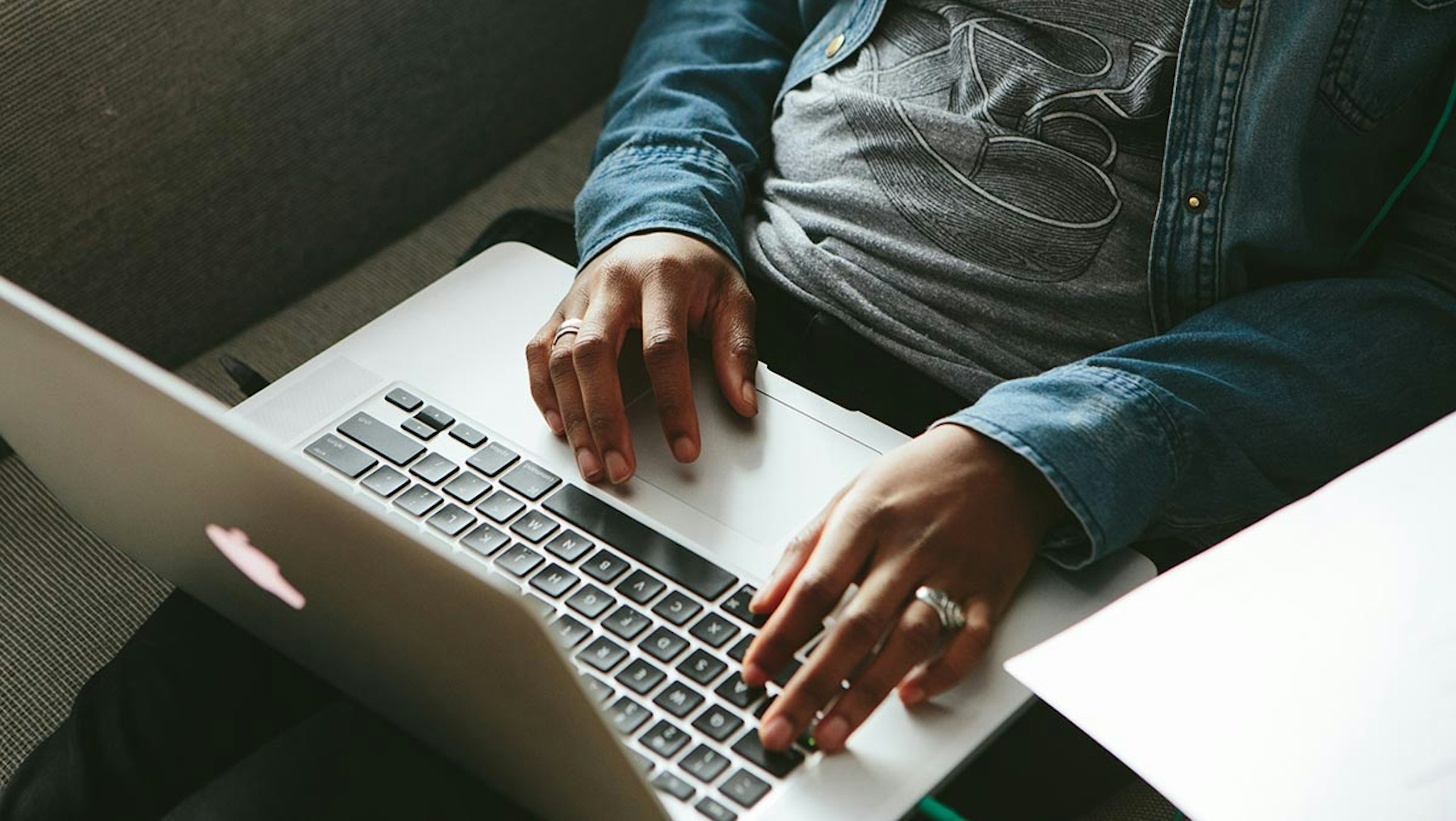 A man types on his laptop while wearing a custom t-shirt