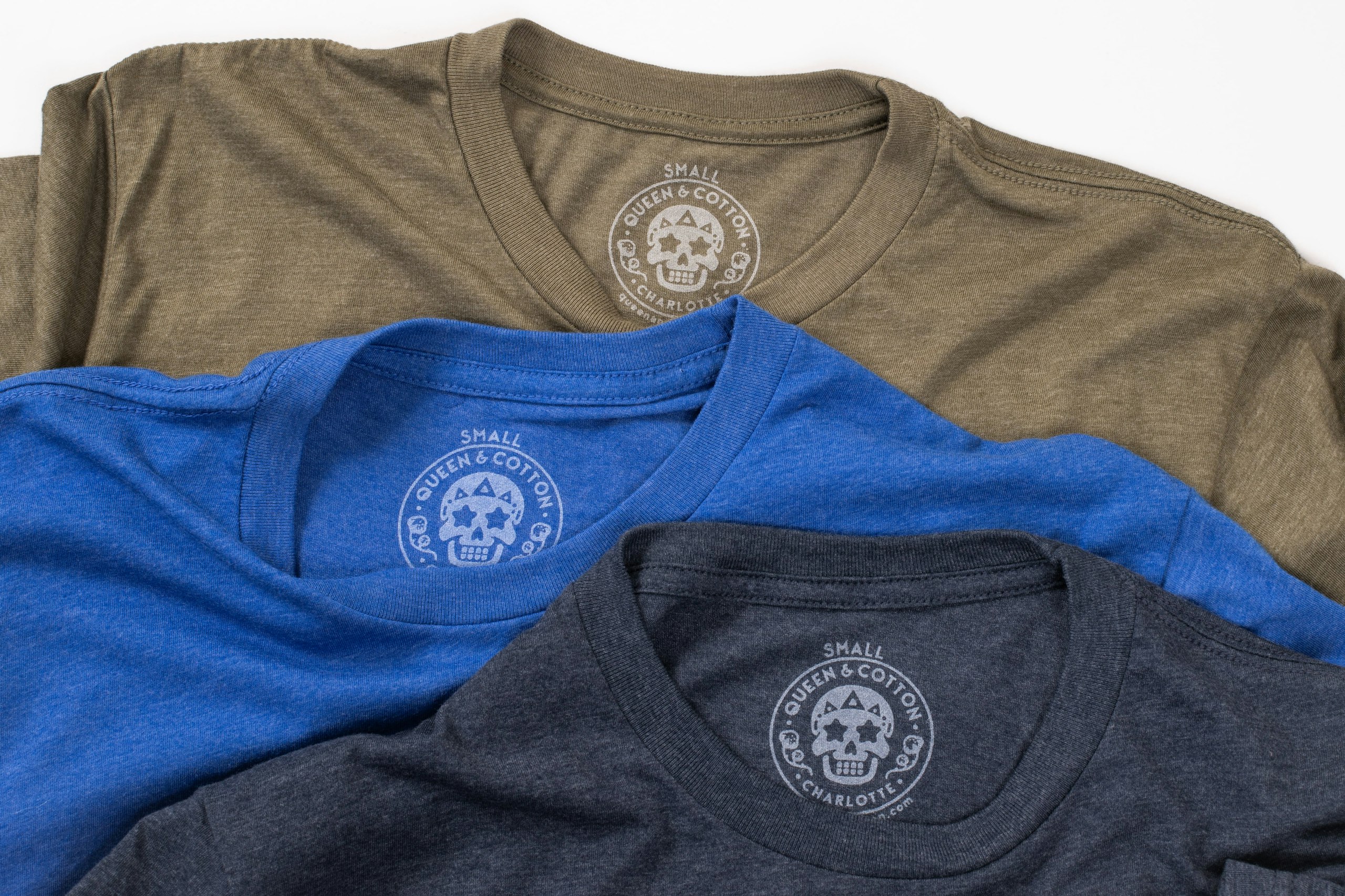 Custom printed tags on a green shirt, a navy shirt, and a royal blue shirt