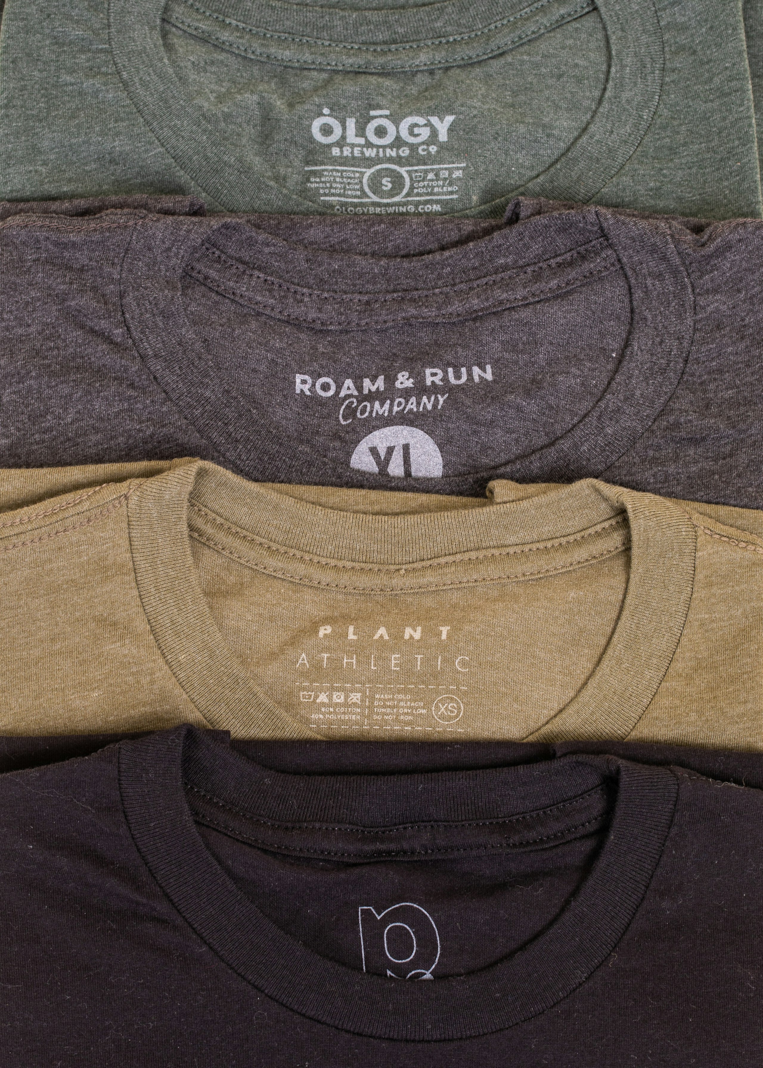 A stack of shirts in multiple colors, all with a heathered look and with custom printed tags