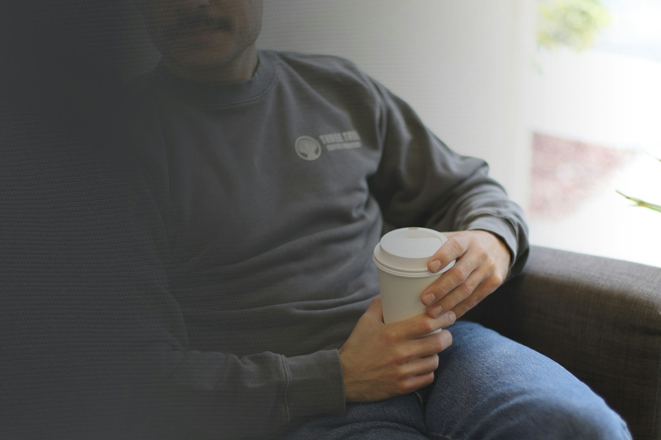 man wearing a grey crewneck sweatshirt with a coffee