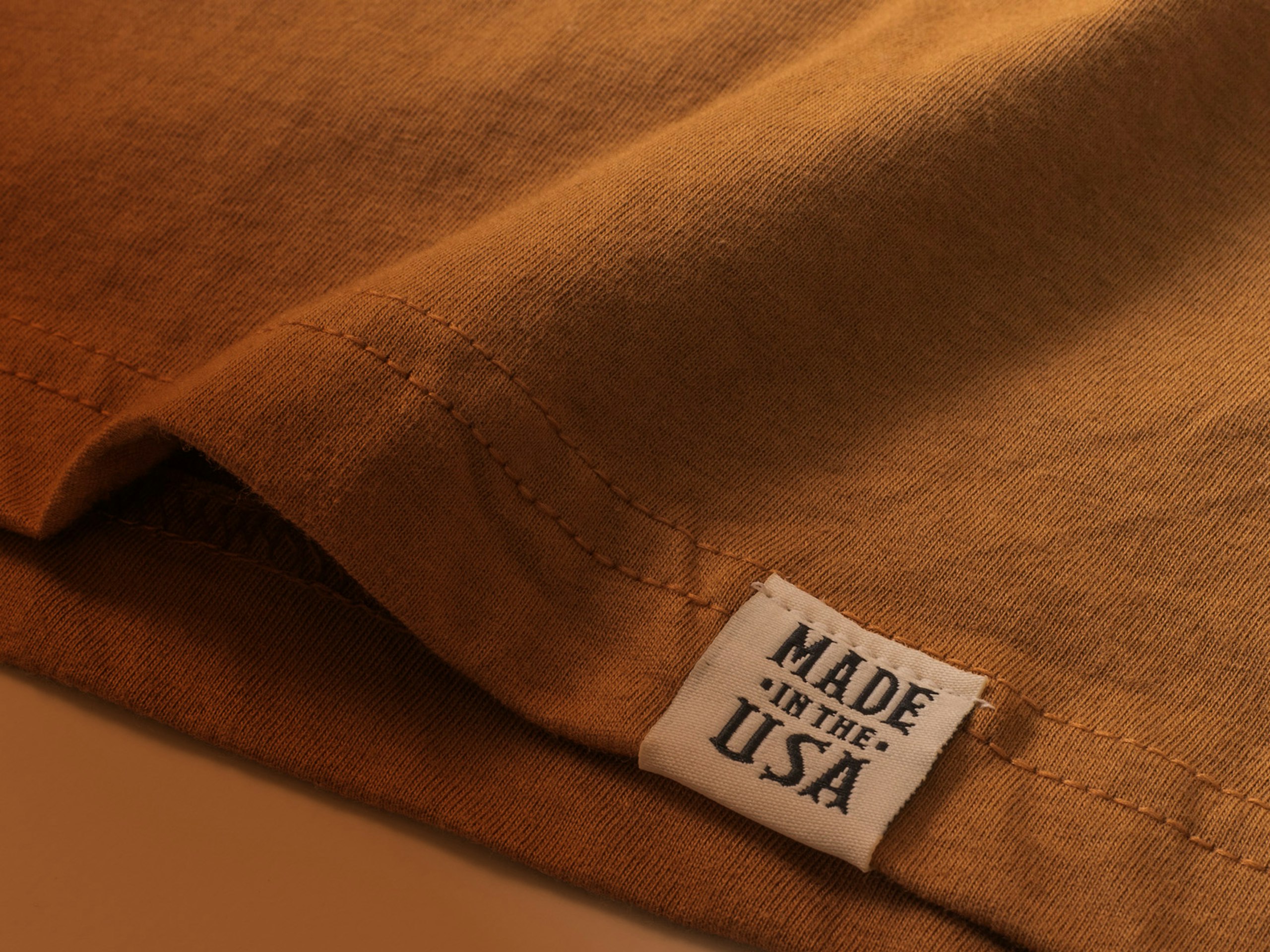 close up of a hem tag on a camel color t-shirt