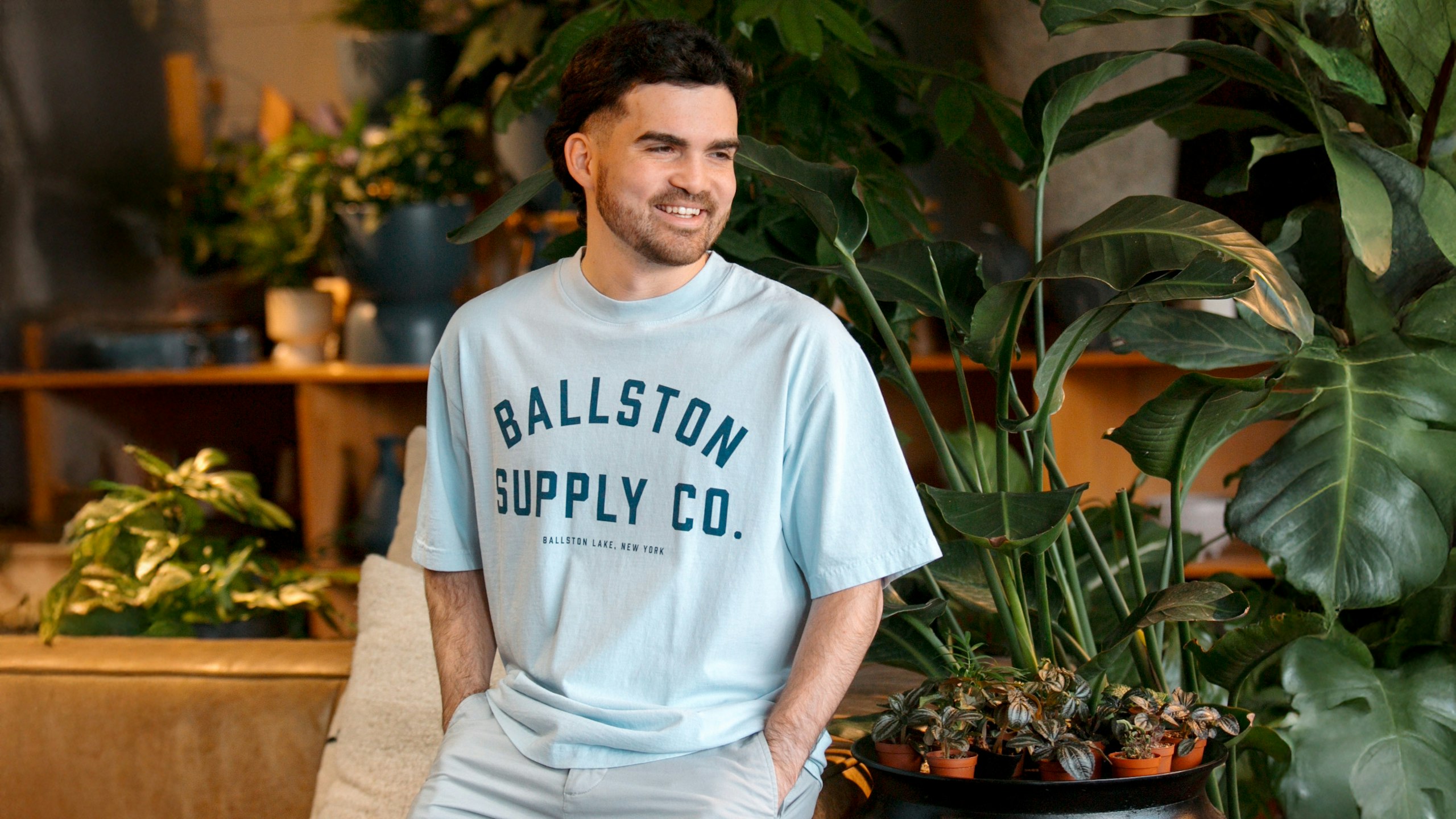 man wearing a light blue tee with the words ballston supply co printed on it