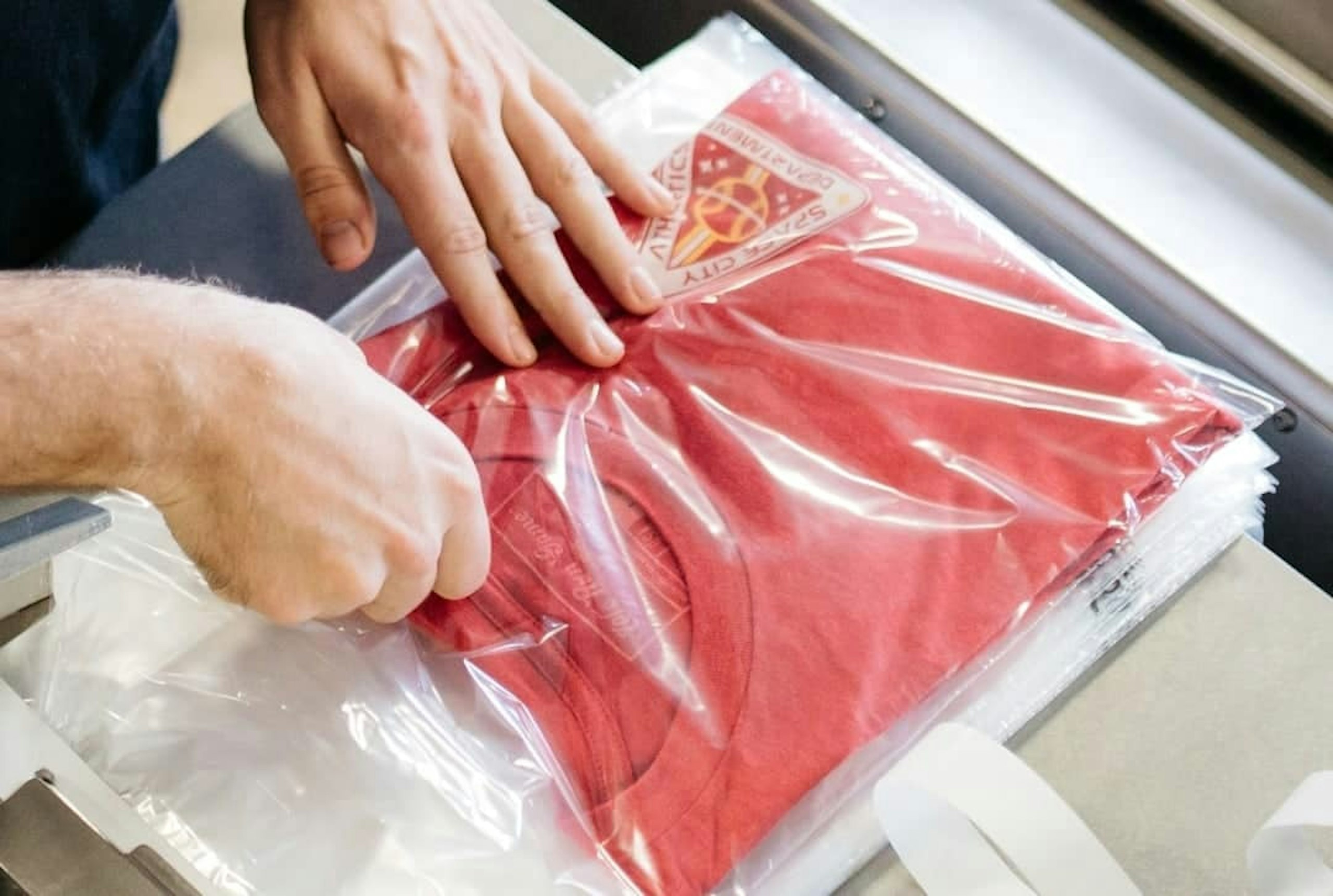 close up of a t-shirt being packed into a polybag