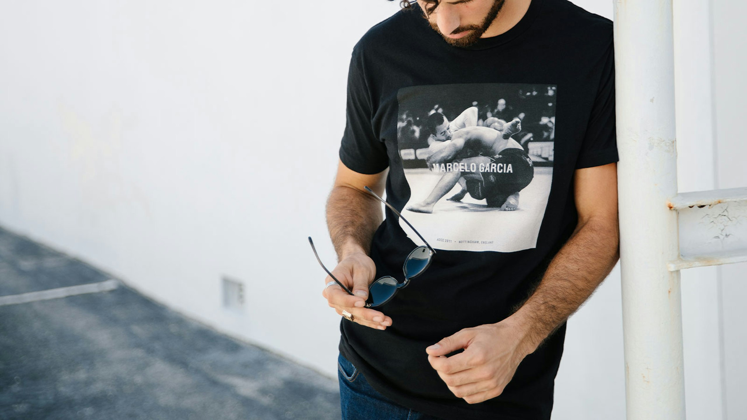 man wearing a black t-shirt - holding sunglasses