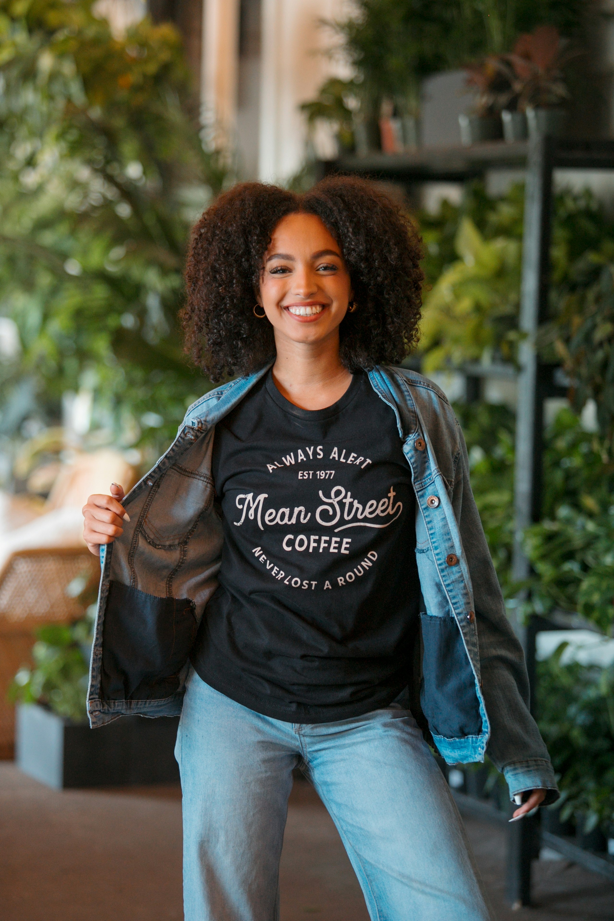 woman smiling while wearing jean jacket and graphic t-shirt