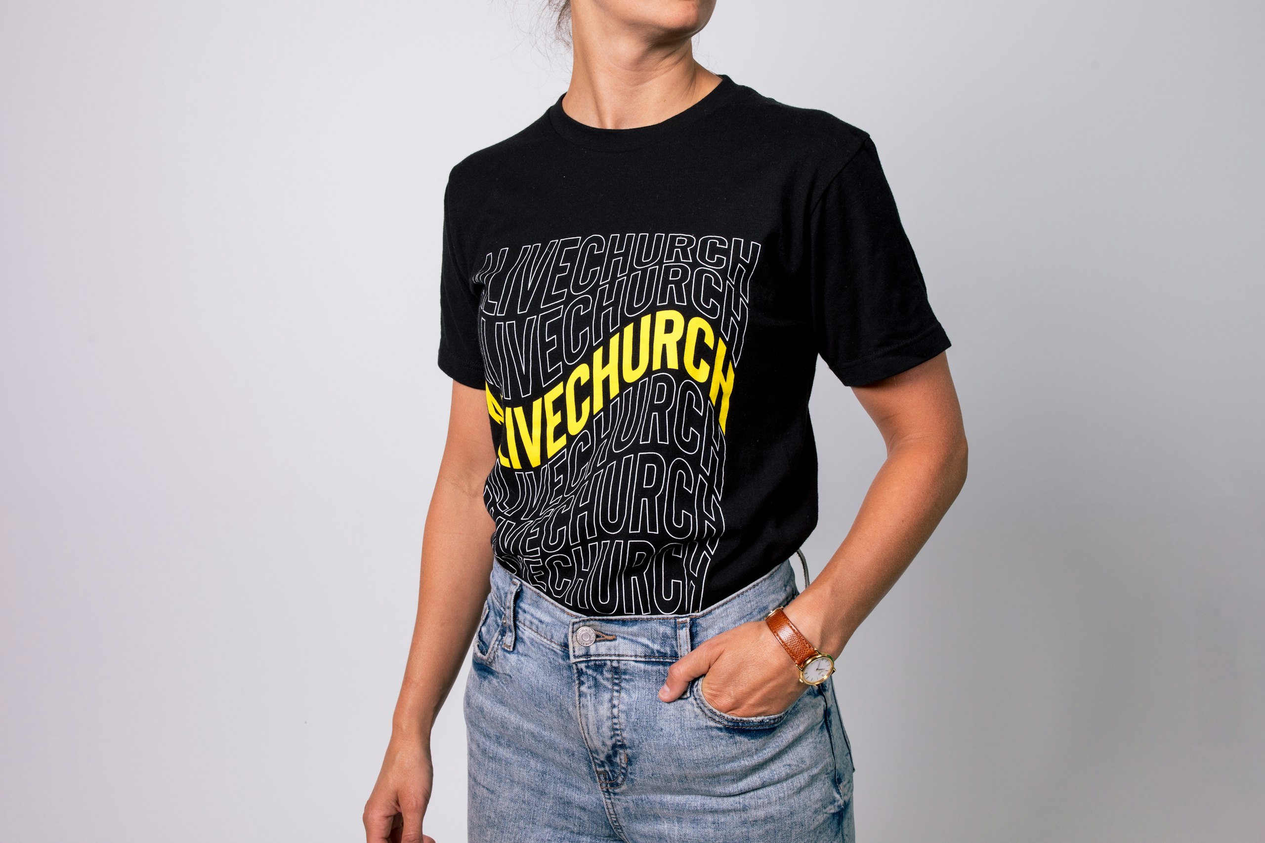 someone wearing a black t-shirt with bright yellow life church printed on it