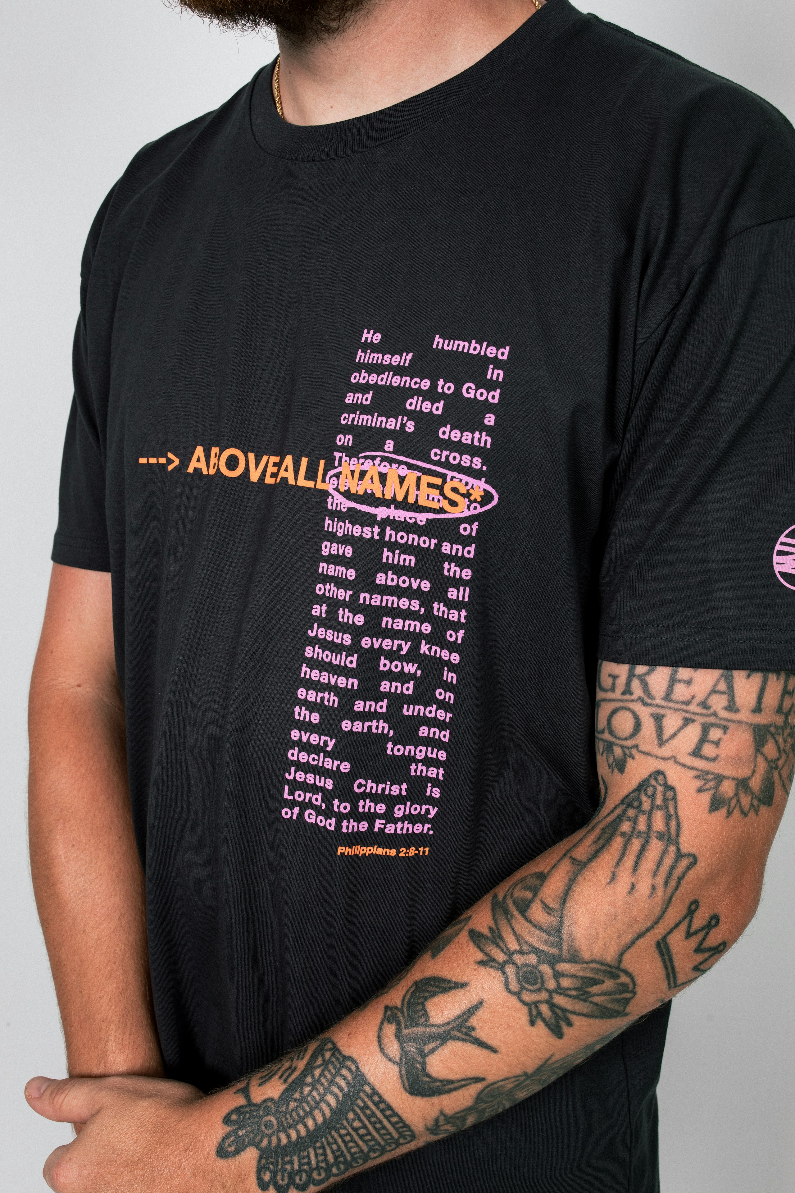 man wearing a black t-shirt with a pink and orange print on the top right