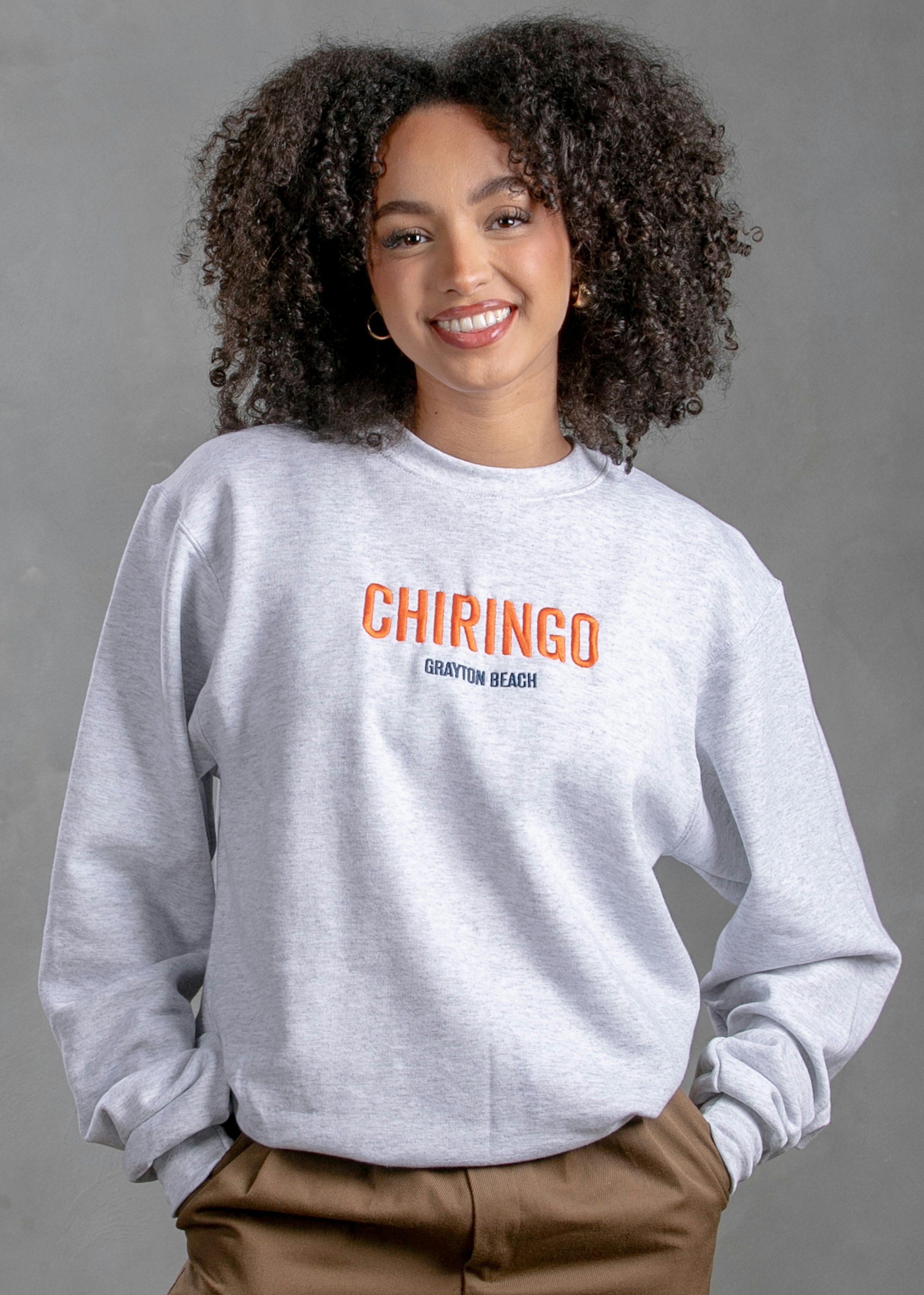 women wearing a white crewneck sweatshirt with the word Chiringo embroidered