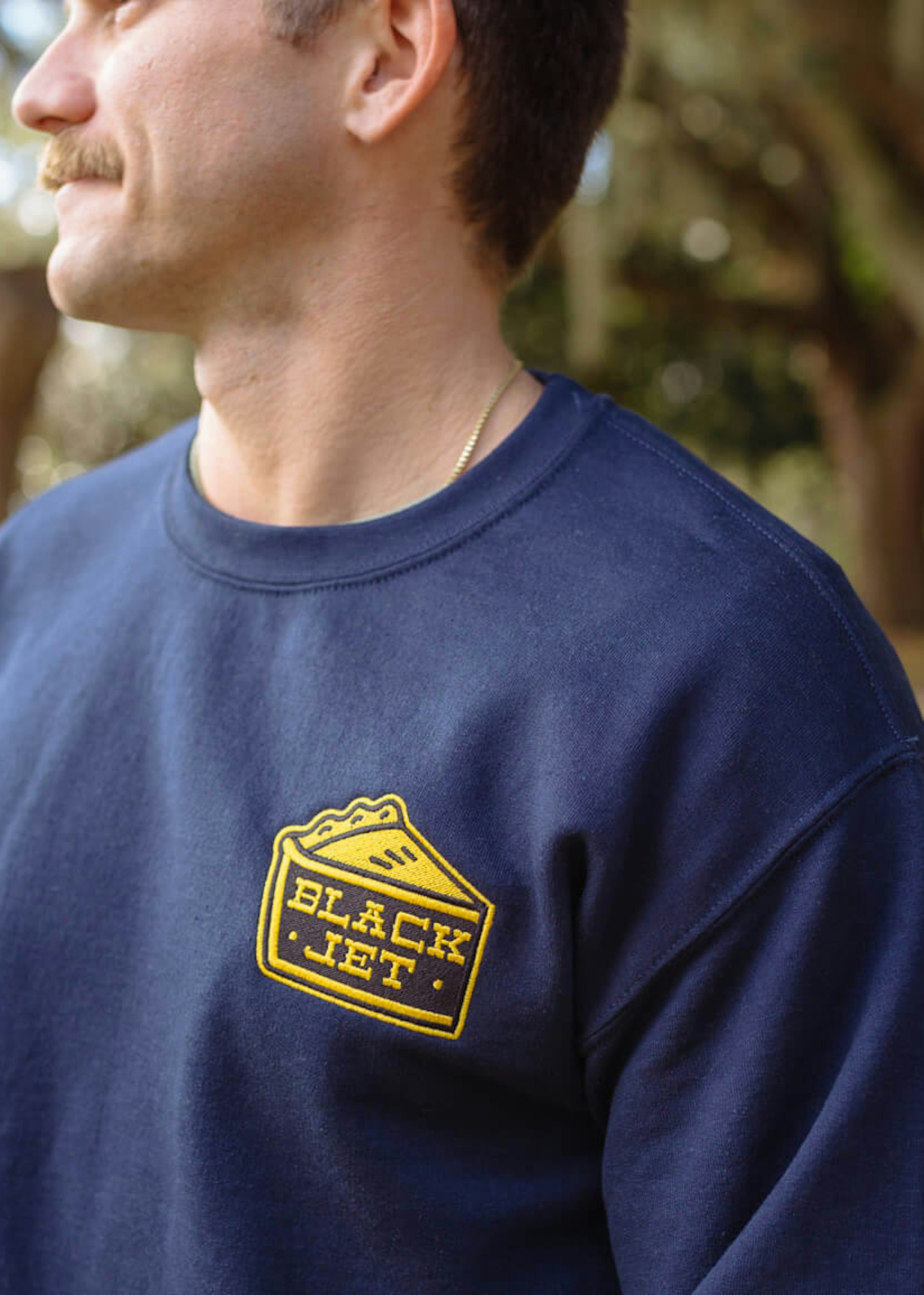 man wearing a navy crewneck sweatshirt with a patch