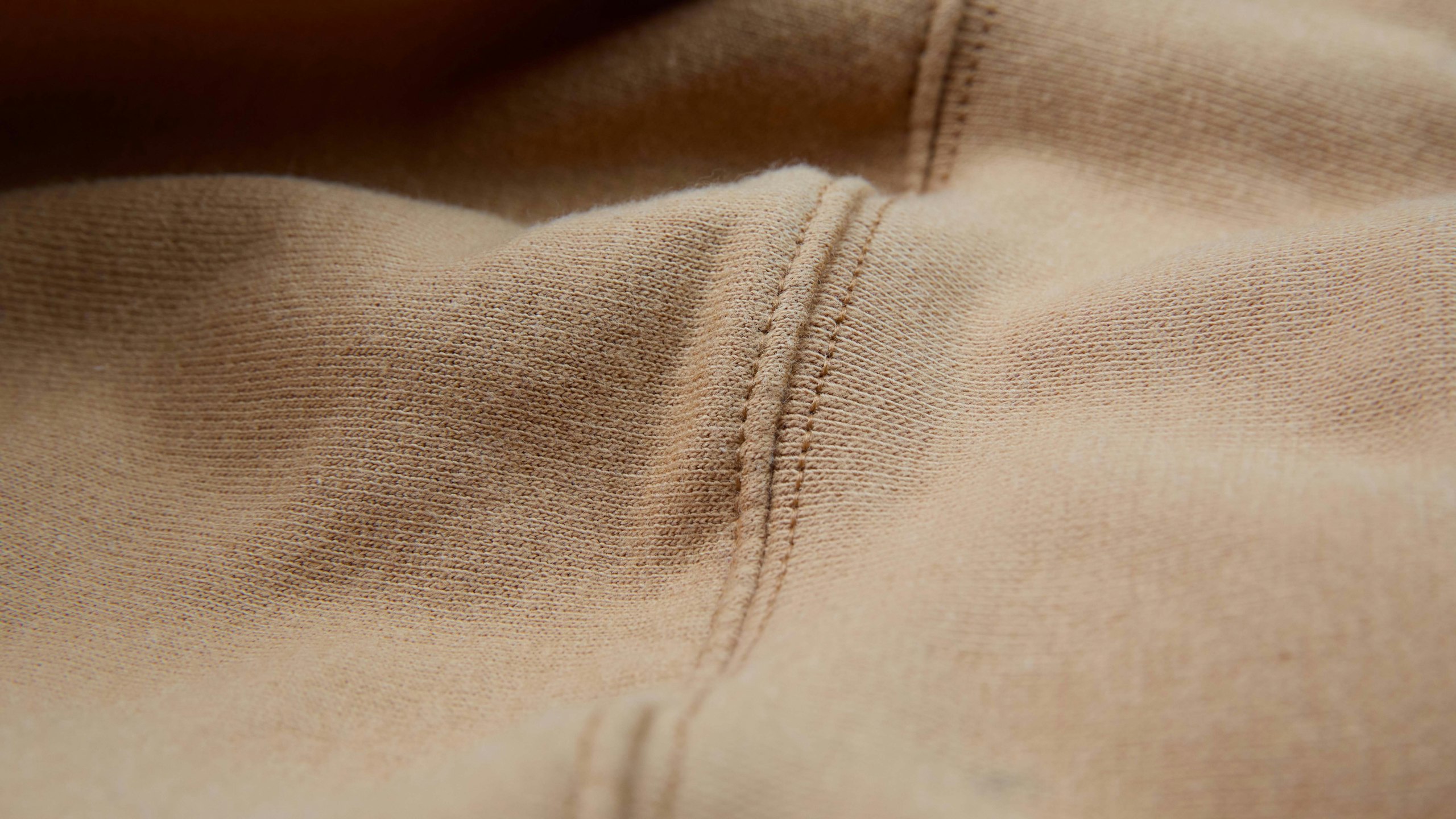 close up on a hoodies seam that is tan