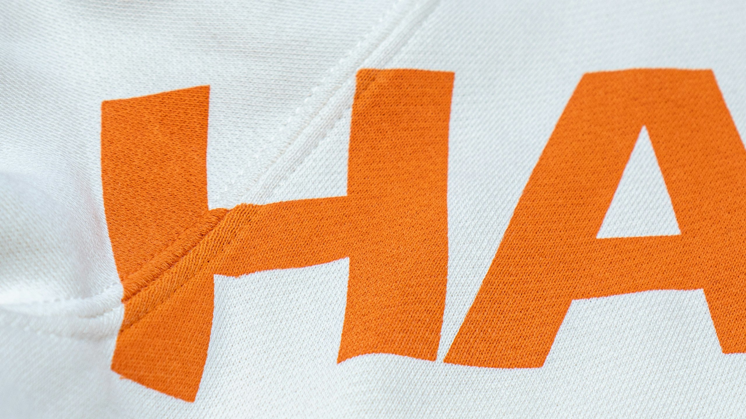 Orange letters H and A printed on white hoodie over the seam