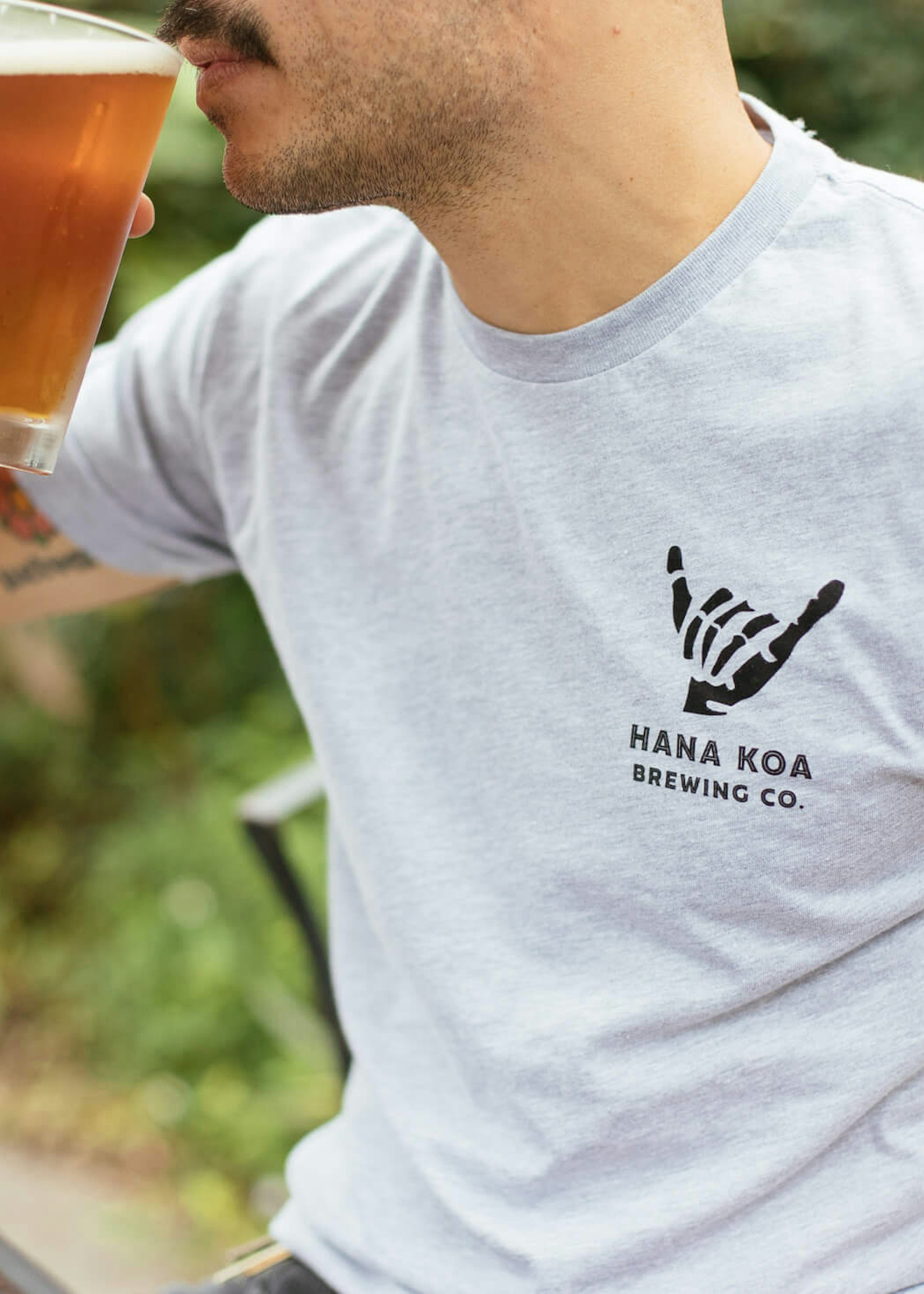 man wearing a white heather tee drinking beer