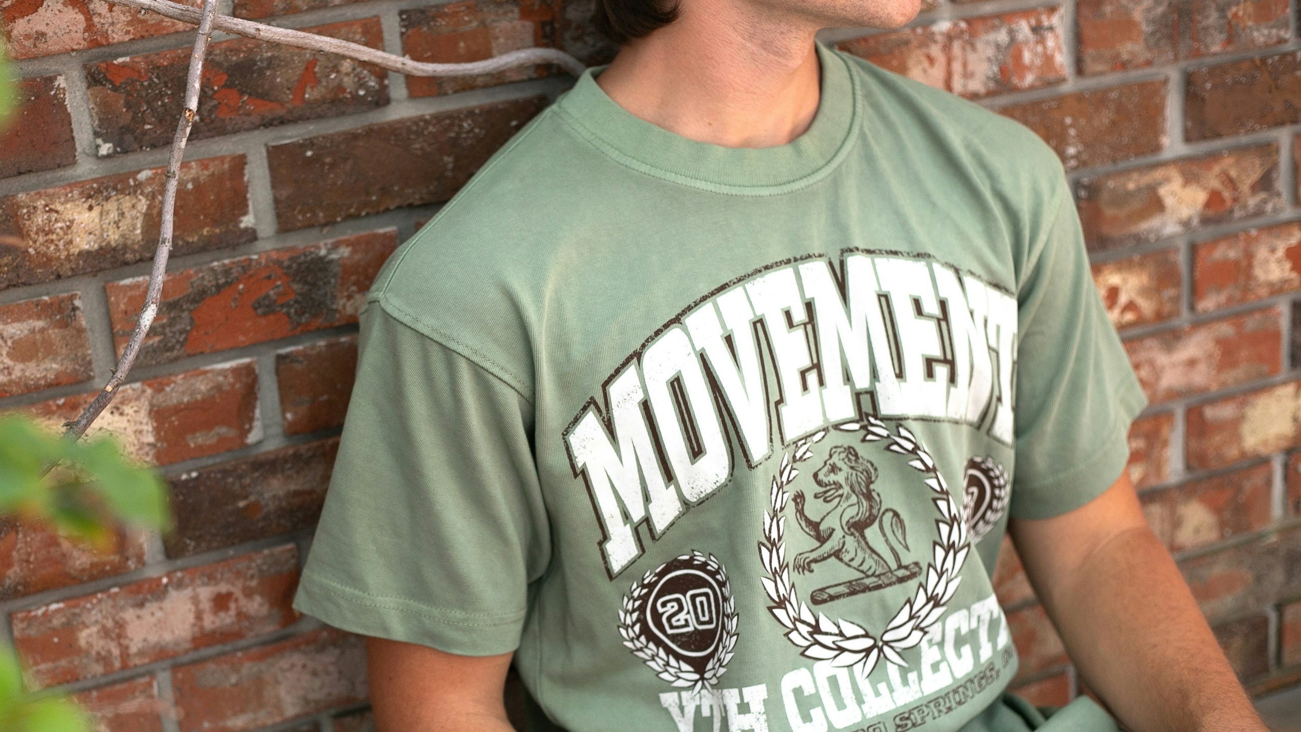 man wearing a green t-shirt with the word movement printed large on the front